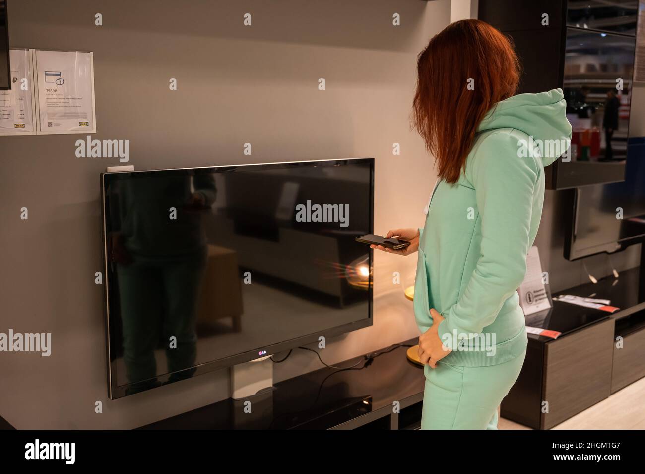 Une femme tient une télécommande de téléviseur dans sa main.La fille choisit des articles d'intérieur dans le magasin IKEA.Novosibirsk.02.26.2020. Banque D'Images