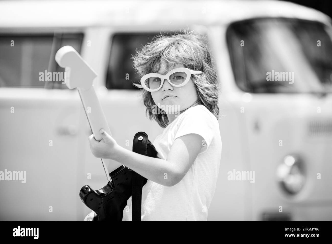 Enfant musicien avec une guitare. Joyeux mignon enfant improvisant. Happy Kid aime la musique sur fond rose coloré. Banque D'Images