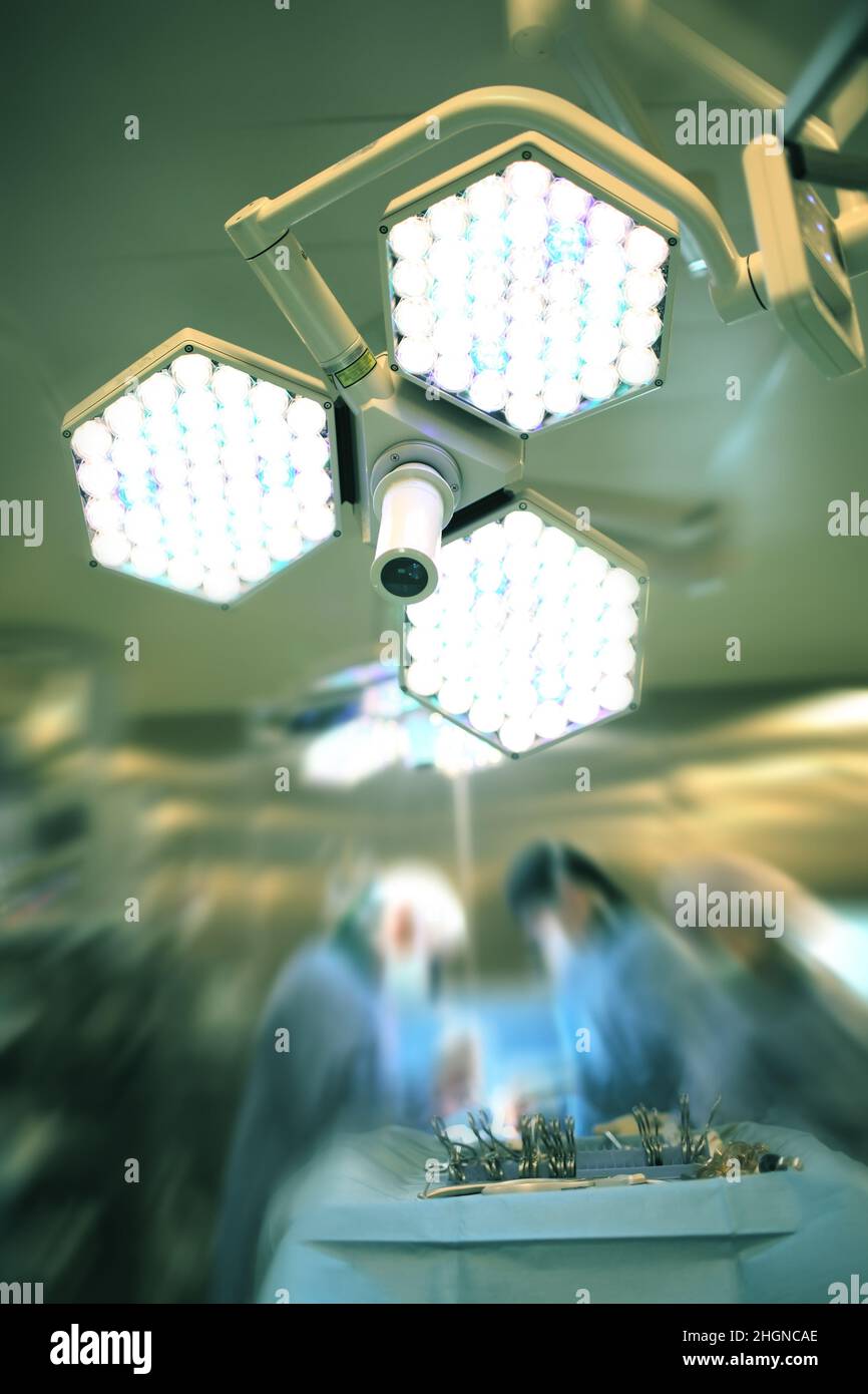 Lumière vive dans la salle de chirurgie sur l'arrière-plan de l'équipe chirurgicale en activité. Banque D'Images