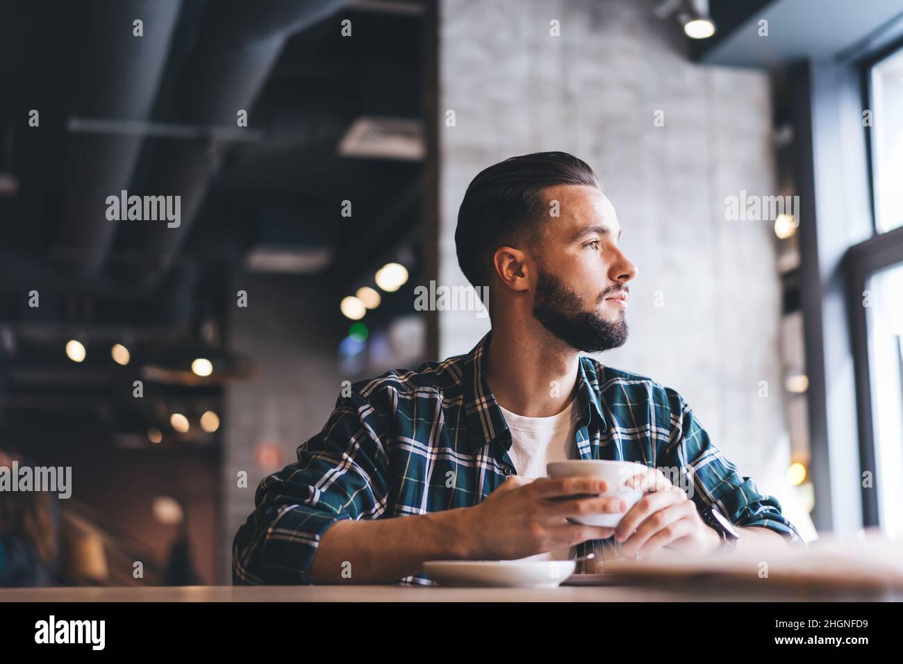 un homme attentionné vêtu d'une chemise tendance qui donne sur l'extérieur pendant l'heure du café dans la région Banque D'Images