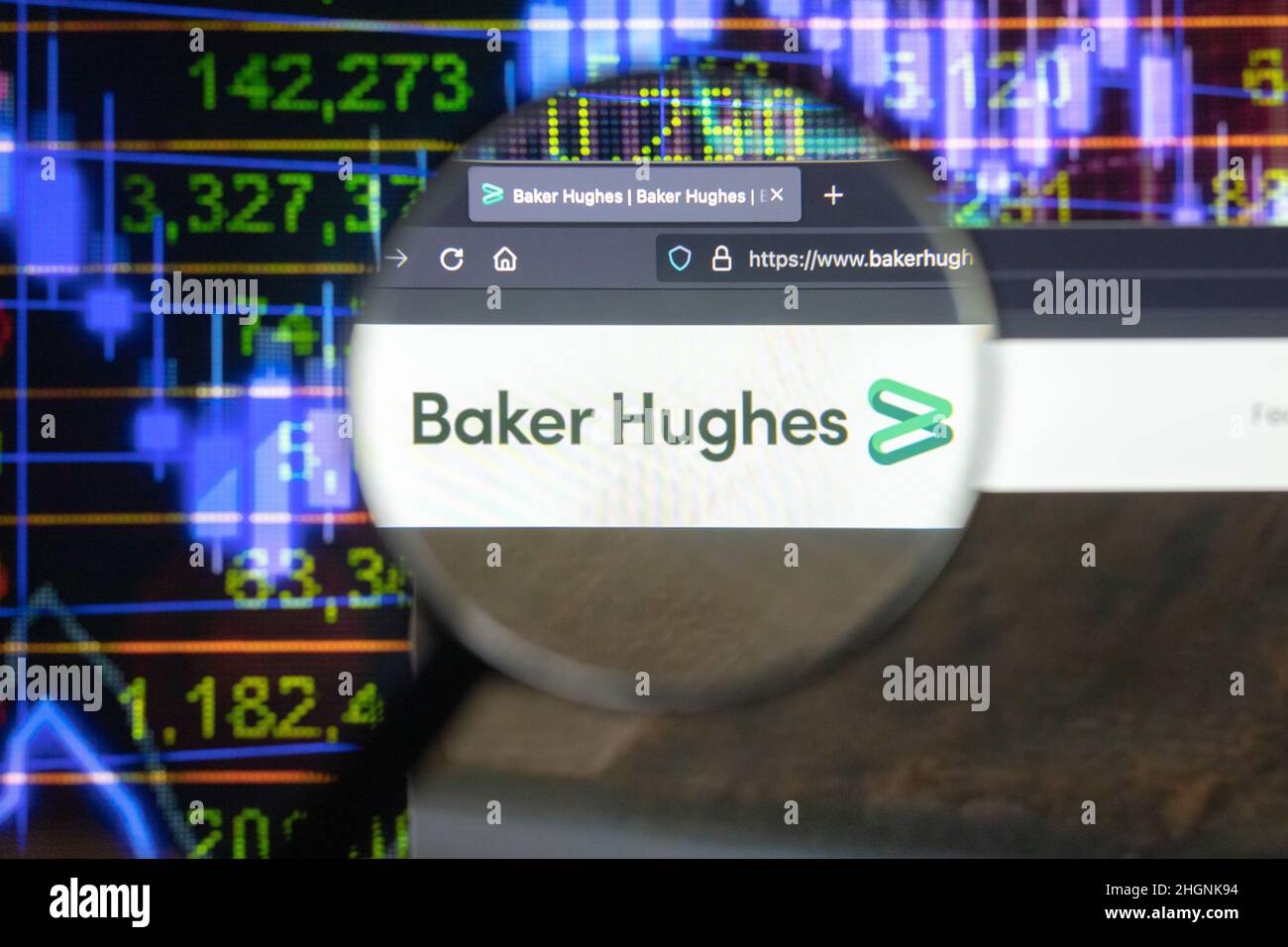 Baker Hughes logo de la société sur un site Web avec des développements flous de marché boursier en arrière-plan, vu sur un écran d'ordinateur à travers une loupe. Banque D'Images