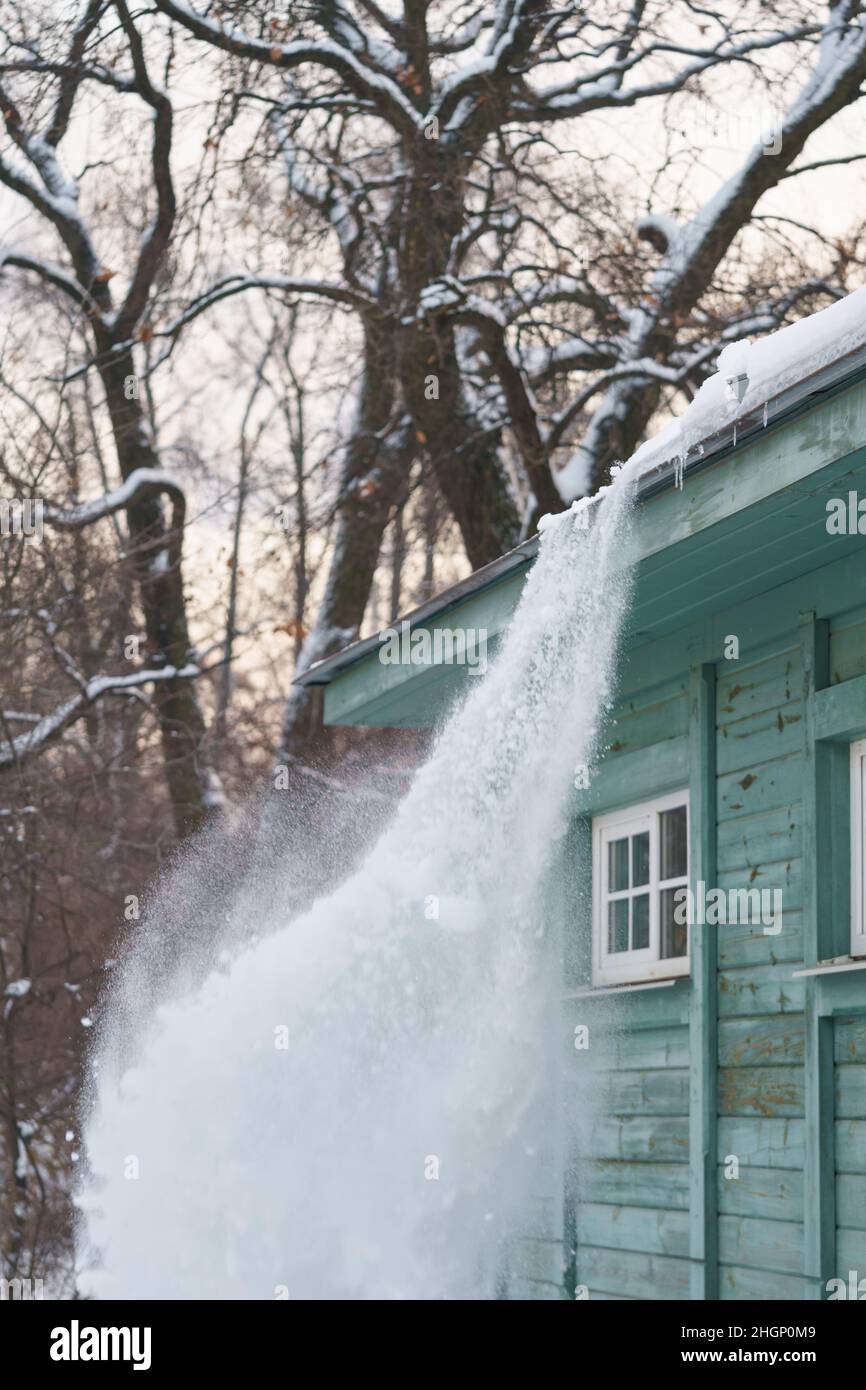 Processus de nettoyage de la toiture de la neige à l'aide d'une pelle.Risque de chute de neige ou de glace sur le toit Banque D'Images