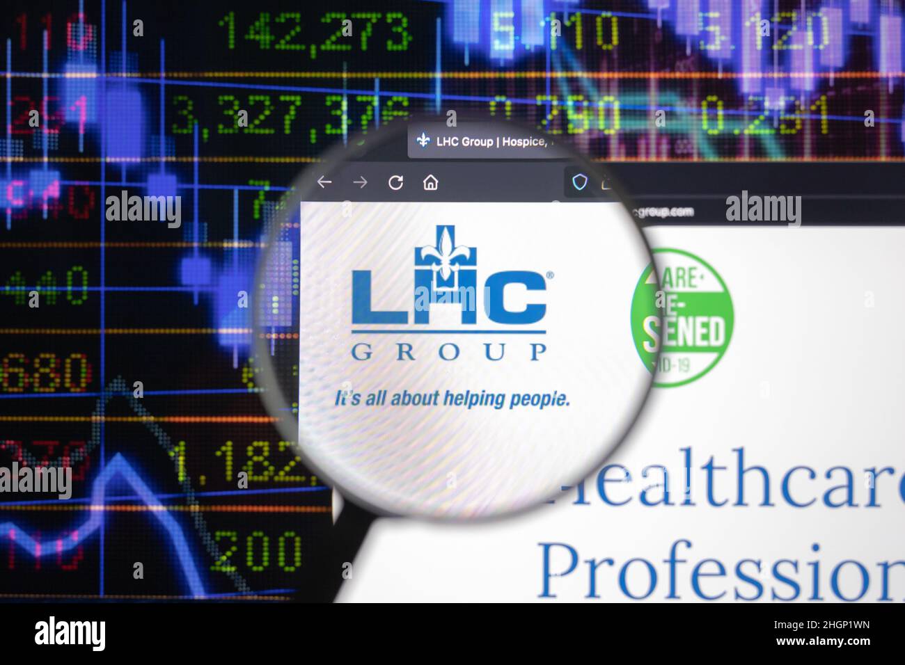 Le logo de la société LHC Group sur un site web avec des développements flous du marché boursier en arrière-plan, vu sur un écran d'ordinateur à travers une loupe. Banque D'Images