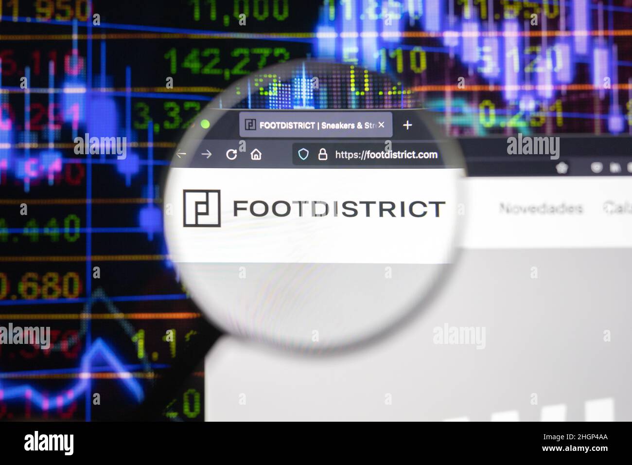 Logo de la société Footdistrict sur un site Web avec des développements flous de marché boursier en arrière-plan, vu sur un écran d'ordinateur à travers une loupe. Banque D'Images