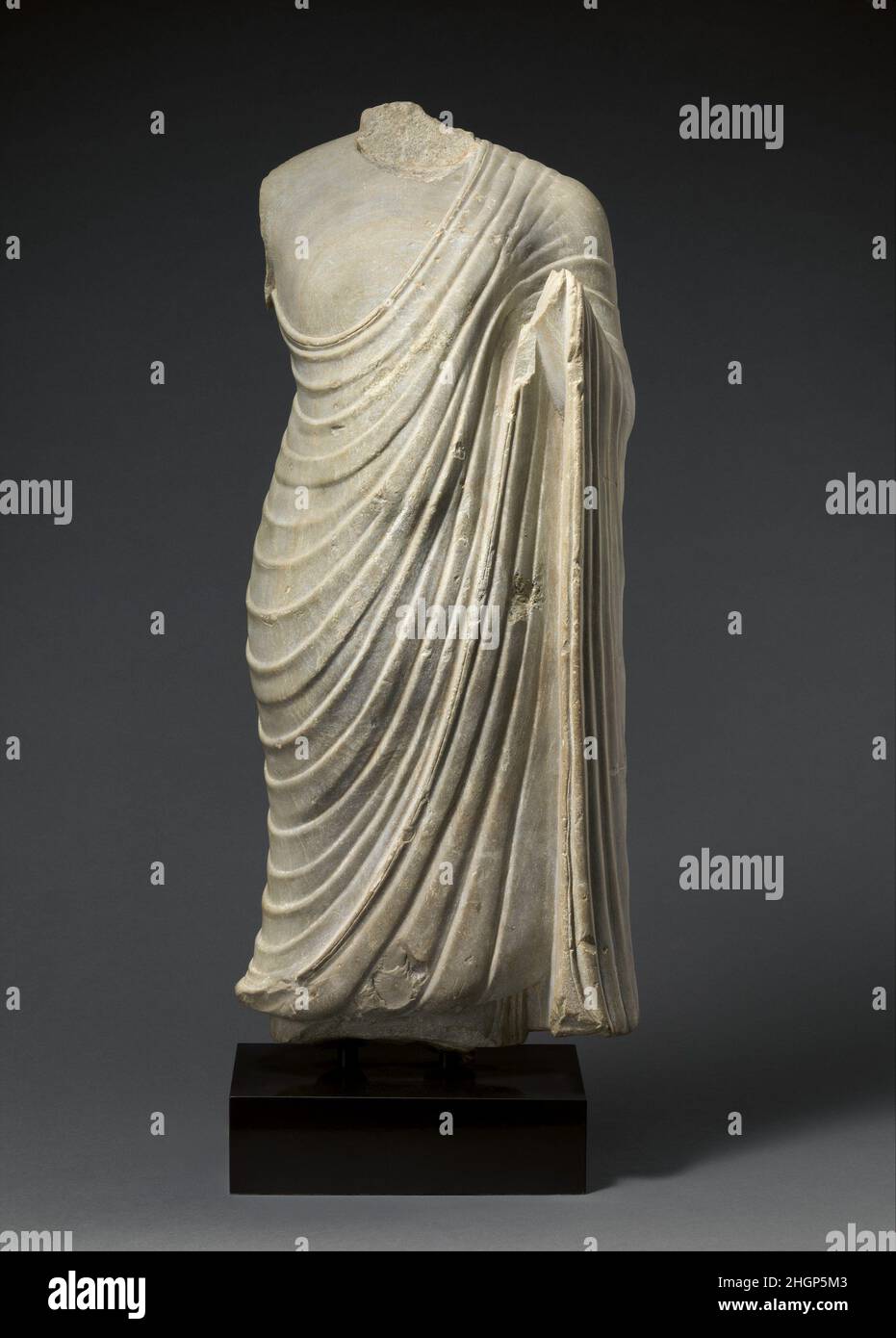 Bouddha 3rd siècle A.D. Inde du Sud (Antique Andhradesa, probablement Nagarjunakonda) cette figure du Bouddha se trouve dans la posture classique du type de figure « règle universelle » (chakravartin).Son puissant physique idéalisé illustre son statut de leader spirituel parmi les hommes.Le geste universel de l'imagerie du Bouddha précoce est celui de la main levée qui étend la protection aux dévotés (abhayamudra), ce qui est ce que ce Bouddha aurait fait dans son état complet.La sculpture est travaillée dans la ronde, avec le flettage profondément coupé des robes monastiques s'étendant complètement derrière.Le «replis gothiques» le TH Banque D'Images