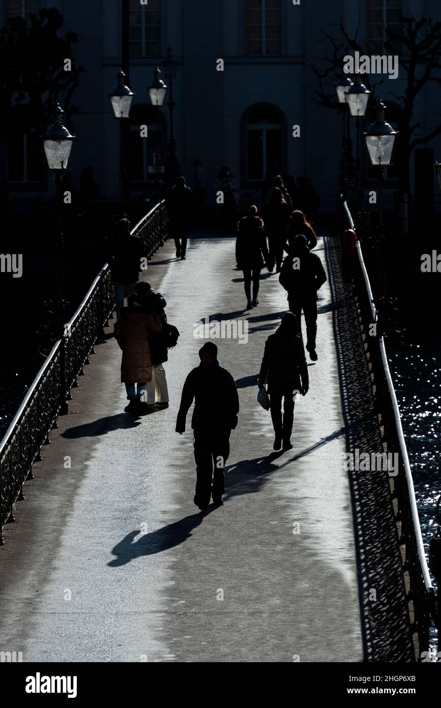 Une vue portrait des piétons sur un pont en silhouette, Lucerne, Suisse. Banque D'Images