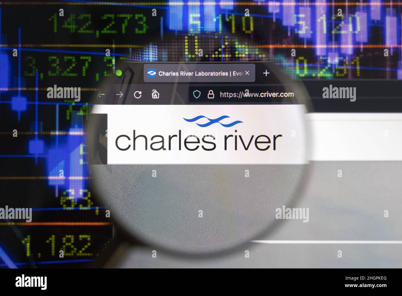 Charles River Company logo sur un site Web avec des développements flous de marché boursier en arrière-plan, vu sur un écran d'ordinateur à travers une loupe. Banque D'Images