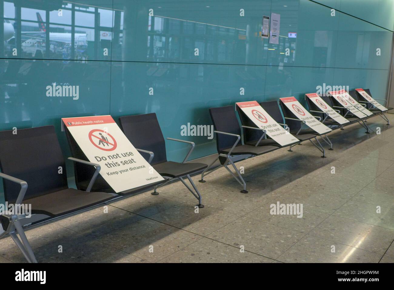 Aéroport international de Heathrow, Londres, Royaume-Uni - Mai 8 2021 : pas de passager sur les chaises d'attente à l'aéroport avec le panneau de signe de social distance sur le dessus Banque D'Images