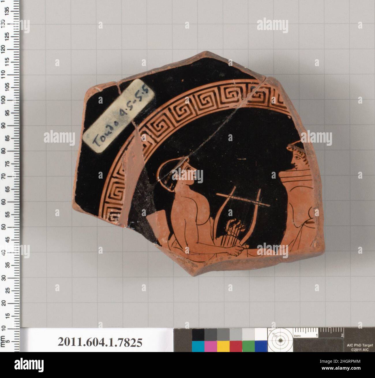 Fragment de terre cuite d'un kylix (coupe à boire) mi-5th siècle avant J.-C. attribué à l'intérieur Sabouroff Painter, avec des jeunes en filets et drapés assis dans une chaise, jouant le lyre; jeunesse en filets à gauche, portant une himation.Fragment de terre cuite d'un kylix (gobelet).Grec, Attique. Mi-5th siècle av. J.-C..Terre cuite, figure rouge.Classique.Vases Banque D'Images