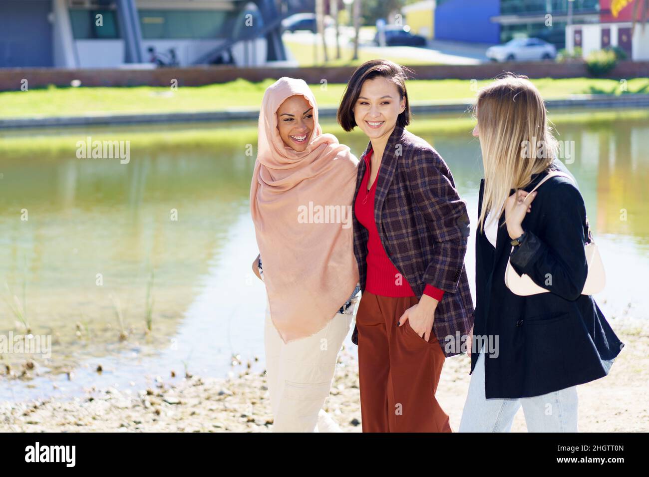 Contenu jeunes femmes multiethniques parlant en se promenant sur les remblais de la ville Banque D'Images