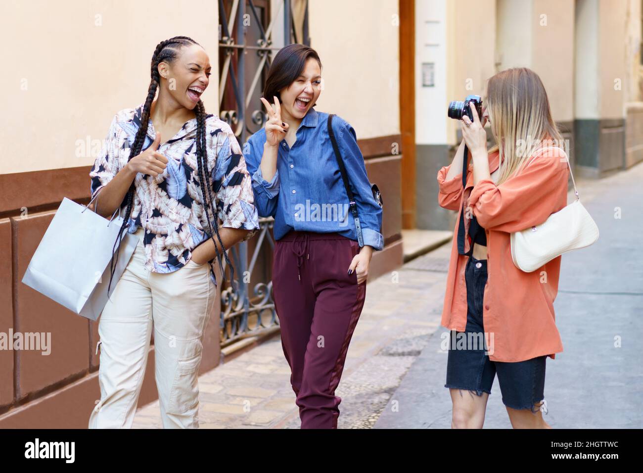 Content dame prenant photo de femmes amies enchantée dans la rue Banque D'Images