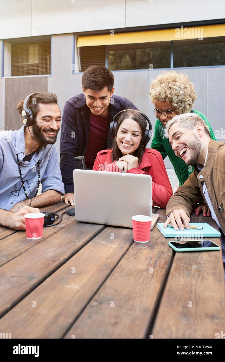 Photo verticale.Appel vidéo d'un groupe de jeunes souriants à l'extérieur en regardant une vidéo sur l'ordinateur portable.Collègues qui diffusent des rencontres Banque D'Images