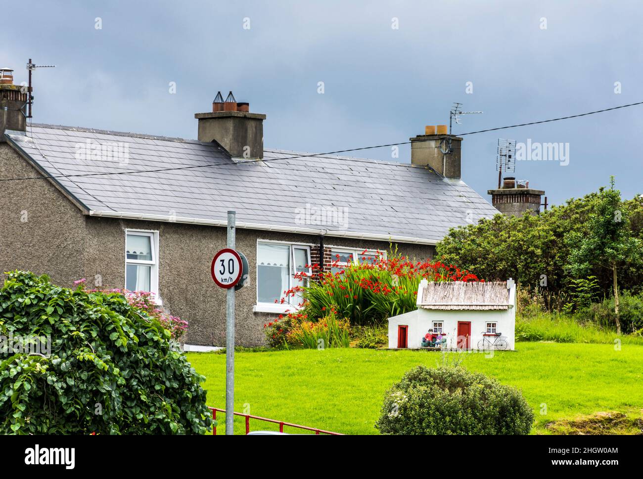 Maison moderne à Glenties, comté de Donegal, Irlande avec petit modèle d'un cottage traditionnel dans le jardin. Banque D'Images
