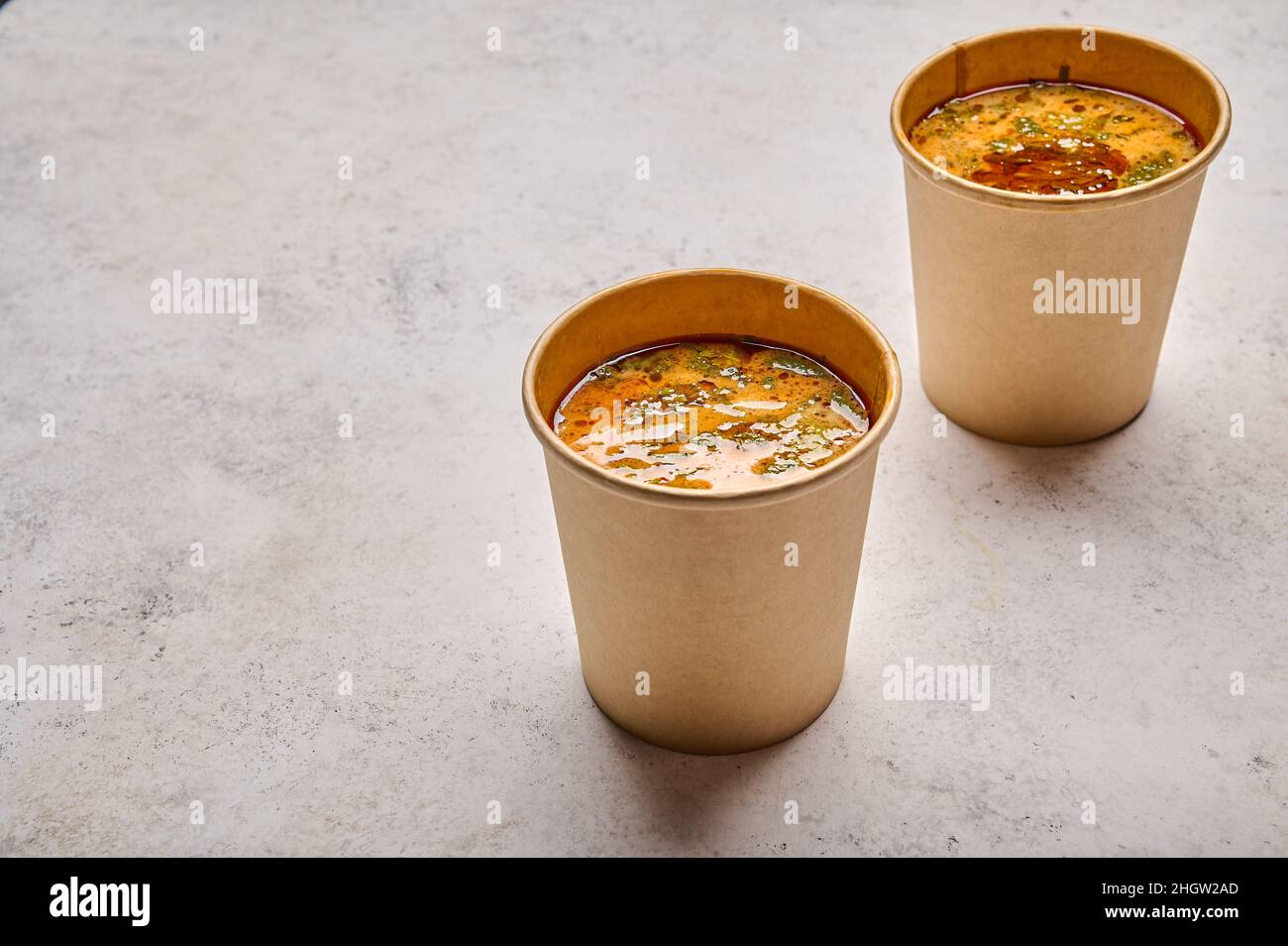Fermez la soupe Tom Yam avec du saumon et des fruits de mer dans deux récipients solides en papier sur fond clair et sélectif.Concept de restauration design à emporter ou à livrer Banque D'Images
