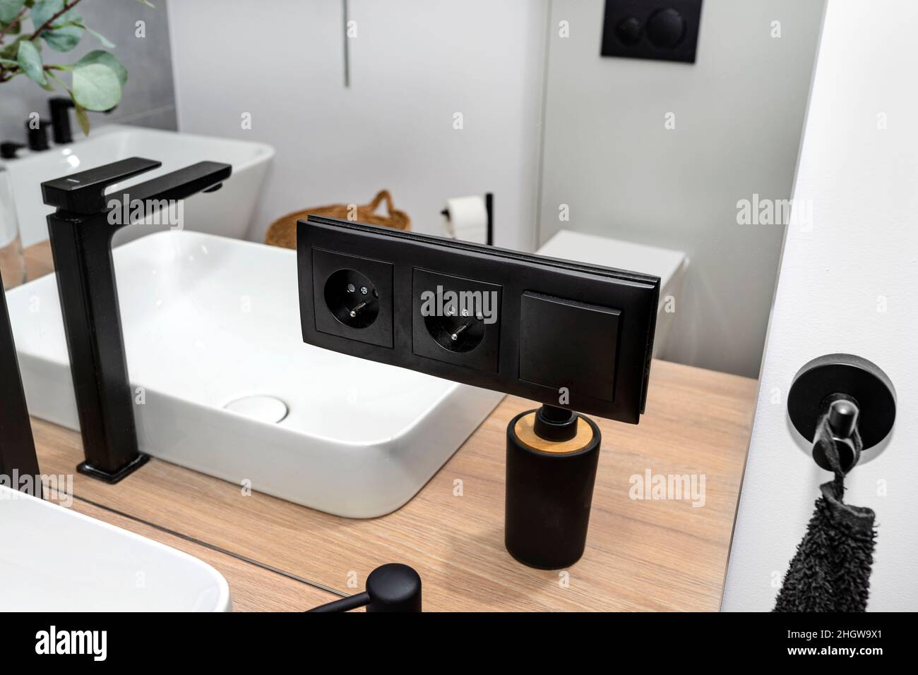 Une prise électrique noire mate et un interrupteur d'éclairage placés dans  le miroir de la salle de bains à côté de l'évier mural, robinet noir  visible Photo Stock - Alamy