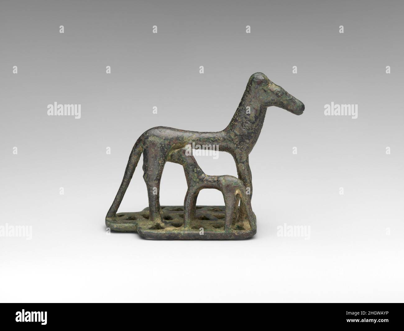 Jument de bronze et foal fin du 8th siècle avant J.-C. grec Une jument qui allaite son foal sur une plinthe rectangulaire avec trois rangées de triangles percés tout droit.Les formes sont cylindriques et caoutchouteuses avec une articulation minimale.Jument et poulain de bronze.Grec. Fin du 8th siècle avant J.-C..Bronze.Géométrique.Bronzes Banque D'Images