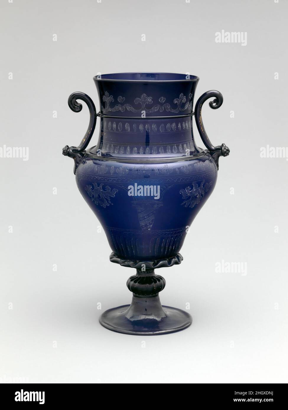 Vase ca.1550–1600 (pied moderne) Austrian, Hall en 1468, le premier empereur Saint-Romain des Habsbourg, Frederick III, a délibérément déposé un vase en verre qui lui a été présenté par le gouvernement vénitien, ce qui implique que ses humbles matériaux étaient indignes de lui.Quelques décennies plus tard, la royauté du Nord courtisait les verriers vénitiens alors qu'ils avaient mis en place des ateliers à Londres, Kassel et le Tyrol.Menaçant le monopole de Venise et divulgeant des secrets professionnels, les verriers italiens ont dû faire face à l'exil de leur patrie.La riche teinte bleue de ce vase, probablement faite par les Vénitiens soutenus par Ferdinand II, Archiduc d'Autriche, Banque D'Images