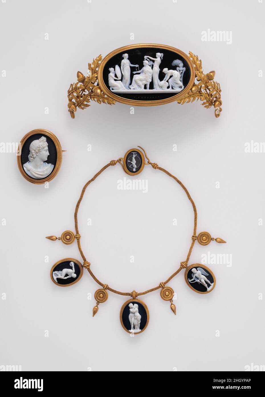 Parure: tiara, collier, et broche mi-19th siècle caméos sculptés par Luigi Saulini Italien Luigi Saulini a appris la sculpture en pierre dure et en coquille de son père adopté, Tommaso (1784–1864),Et a continué dans le commerce de famille d'un magasin réussi dans la via del Babuino à Rome.Cameo-les parures qui comprenait tiaras est devenu à la mode parmi les sœurs de Napoléon et les dames de sa cour.Le goût a survécu pendant au moins un demi-siècle.Un peu de papier qui accompagnait l'ensemble lorsque Weil l'a prêté au Metropolitan Museum en 1929 a déclaré que les montages étaient conçus par John Gibson (1790–1866), un BR Banque D'Images