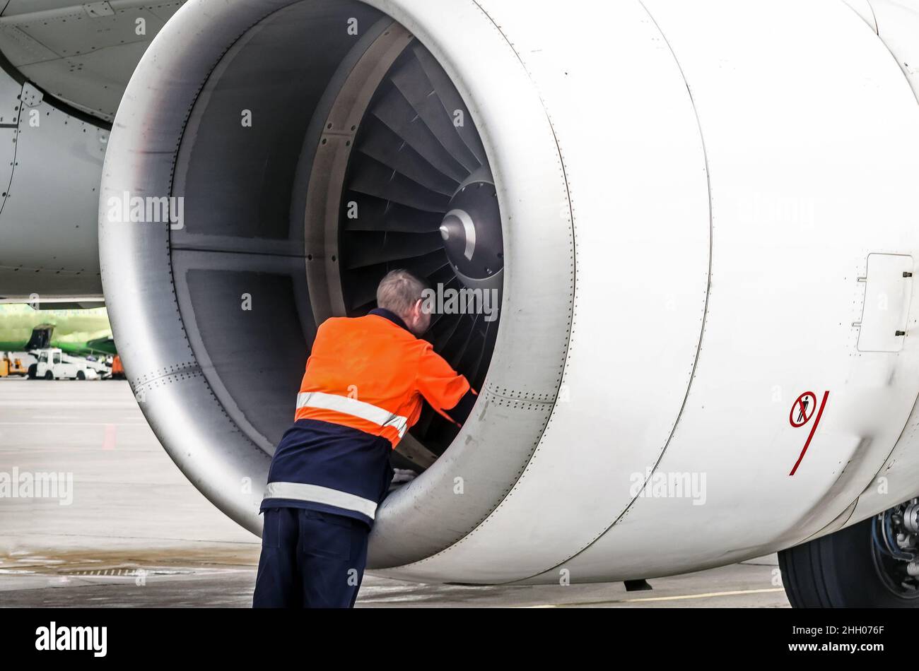 Un technicien en entretien vérifie la lame de l'avion du moteur de turbine après le voyage et le psodki dans le parking de l'aéroport Banque D'Images