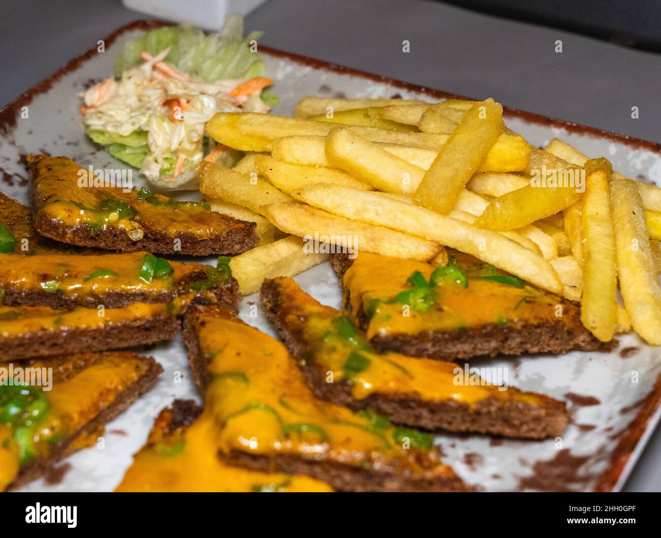 Mise au point sélective de frites et de petites tranches de pain grillé au piment sur une assiette de hors-d'œuvre. Banque D'Images