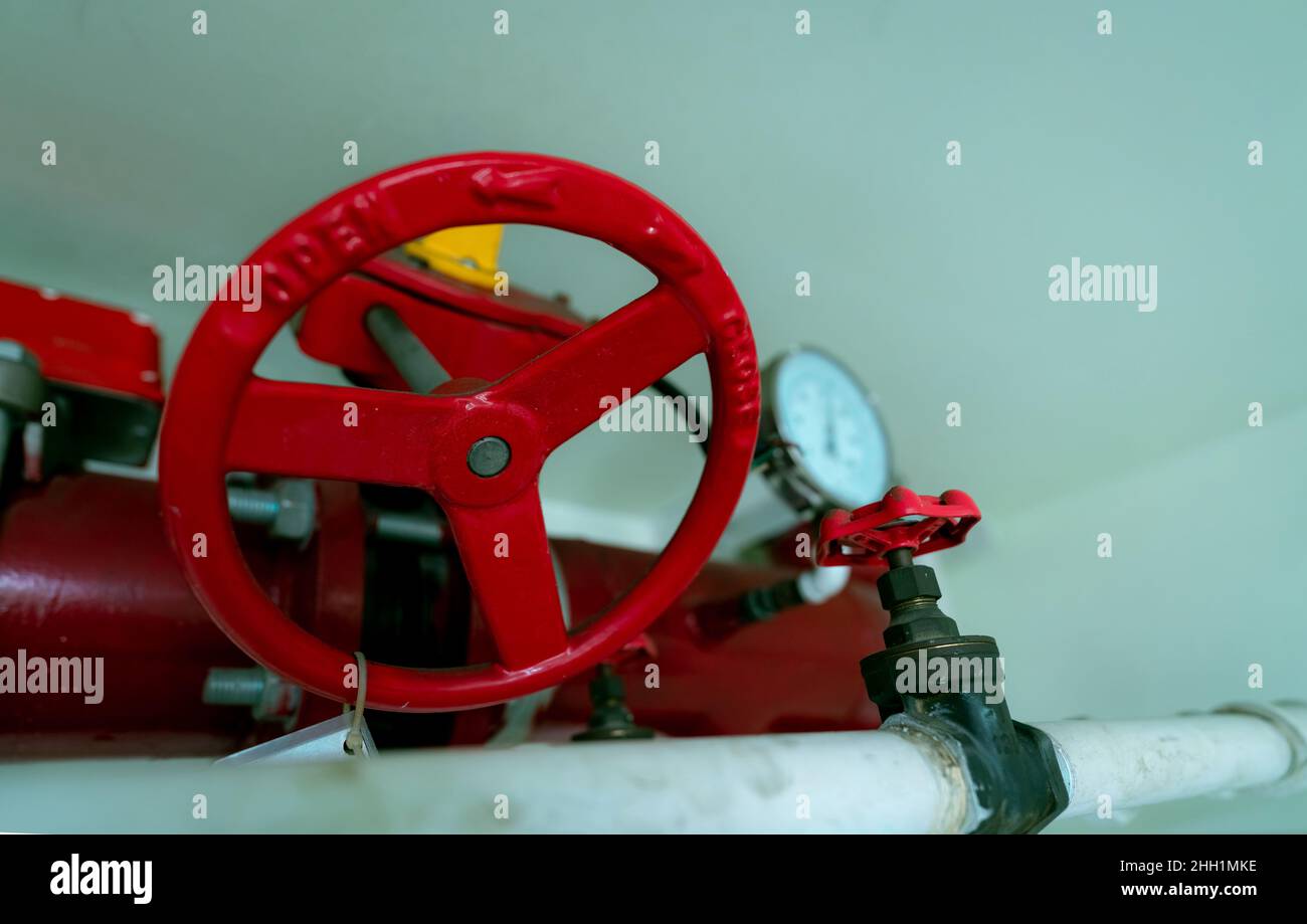 Volant rouge de la tuyauterie principale d'alimentation en eau dans le système d'extinction d'incendie et tuyau d'alimentation en eau blanc.Système de gicleurs d'incendie avec tuyaux rouges suspendus Banque D'Images