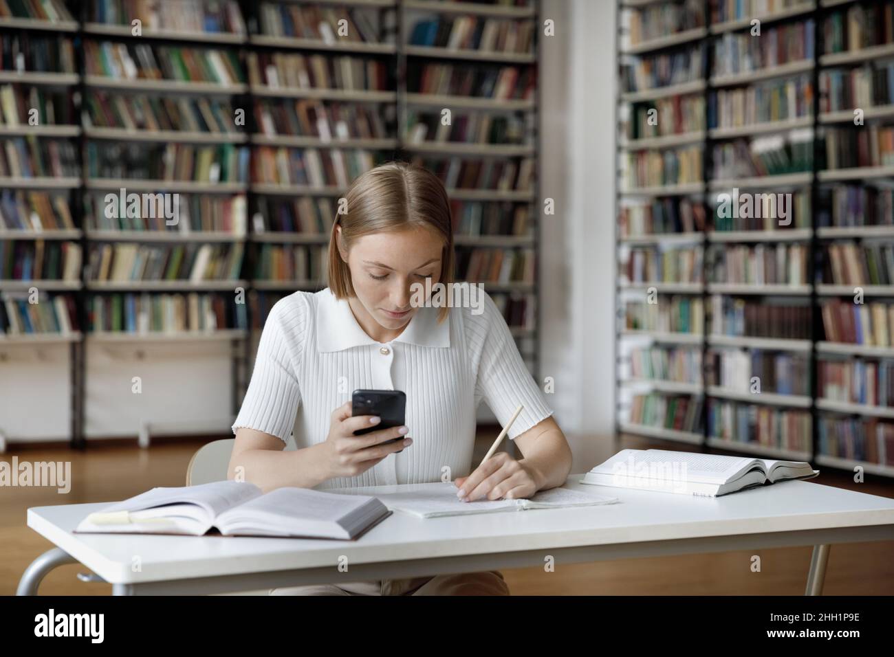 Une jeune fille étudiante diplômée et travailleur concentrée faisant ses devoirs à l'étude Banque D'Images