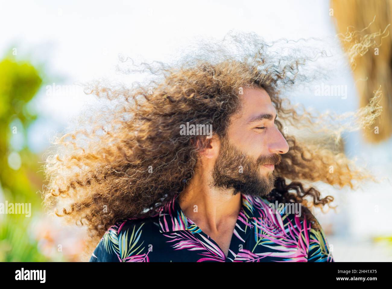 Un homme barbu et à tête bouclés d'afro vole en plein air Banque D'Images