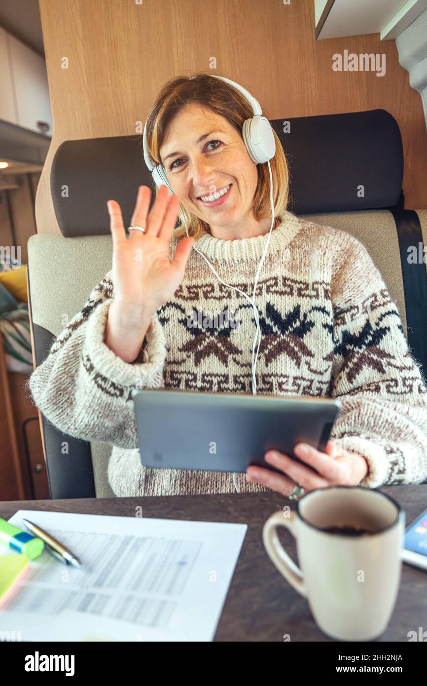 Femme agitant en regardant la caméra lors d'un appel vidéo depuis son camion Banque D'Images