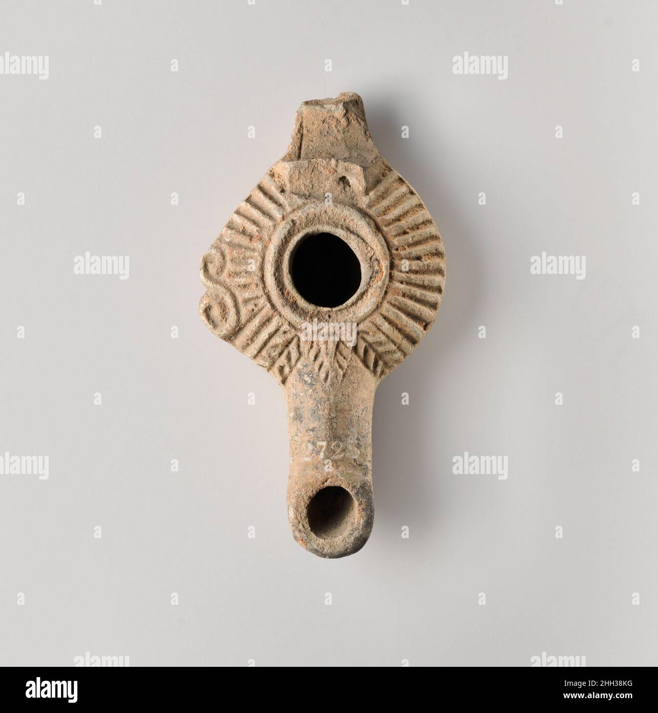 Lampe à huile en terre cuite grecque moulée, avec grande poignée en anneau.Grand trou de remplissage central, entouré de deux rainures concentriques ; sur l'épaule oblique, lignes rayonnées rayonnantes, avec bouton en forme de S sur le bord gauche ; buse longue, avec trou de mèche circulaire et flanquée à l'arrière avec des chevrons et, sur le dessus, avec une petite feuille triangulaire à motifs.Anneau de base incisé et base inégale.Corps et buse complets ; la plupart des poignées sont manquantes.Lampe à l'huile en terre cuite.Grec.Terre cuite.Hellénistique.Terracottas Banque D'Images