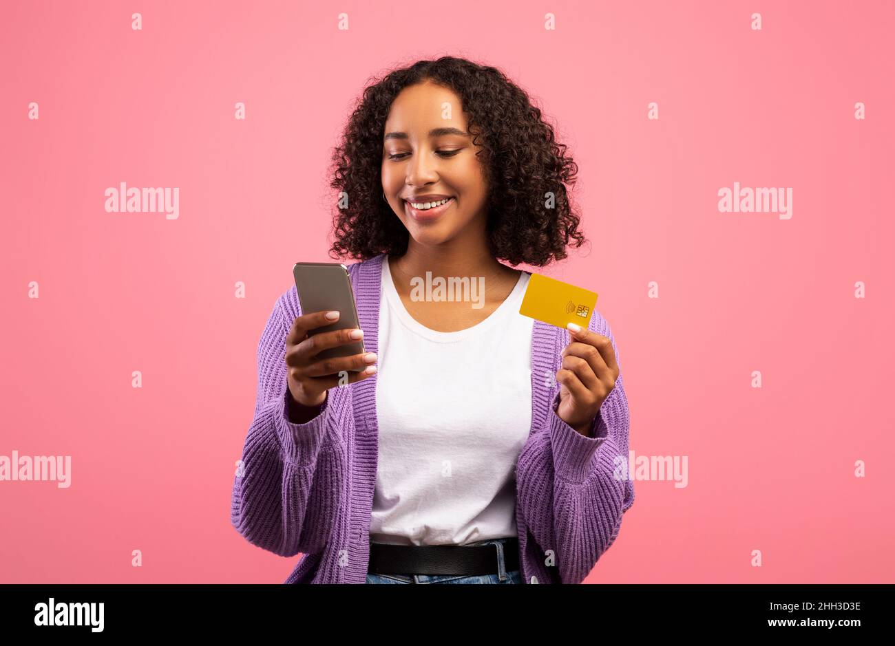 Nouvelle application d'achat en ligne.Charmante femme noire utilisant un smartphone et une carte de crédit, achetant des biens dans la boutique Internet Banque D'Images