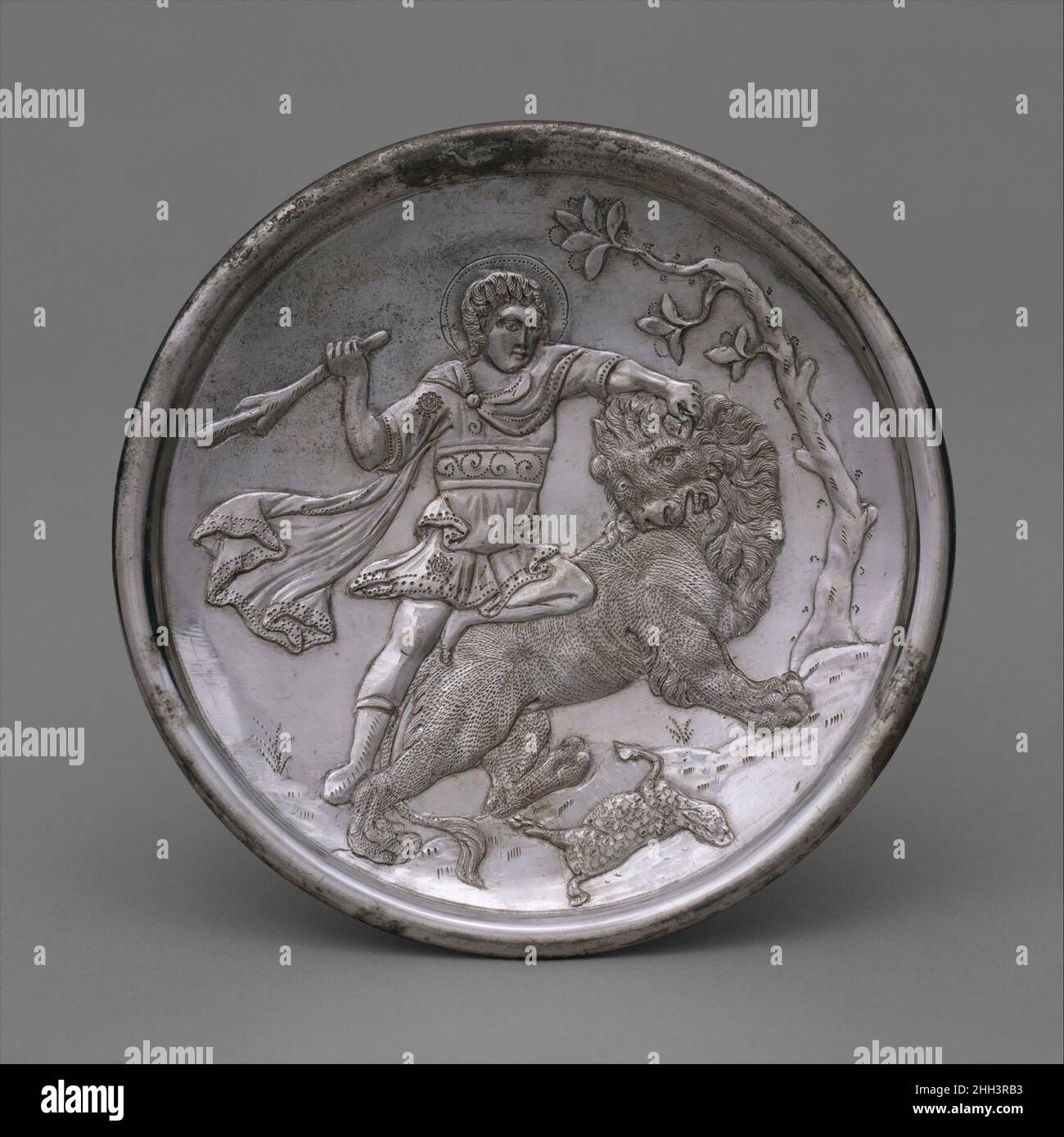 Assiette avec David en laçant un Lion 629–630 byzantin en 628–29 l'empereur byzantin Herakleios (r.610–41) a mené avec succès une longue et coûteuse guerre avec la Perse et a retrouvé Jérusalem, l'Égypte et d'autres territoires byzantins.Les timbres d'argent datant de 613–29/30 au dos de ces chefs-d'œuvre placent leur fabrication au règne d'Herakleios.Les figures bibliques sur les plaques portent le costume de la première cour byzantine, suggérant au spectateur que, comme Saül et David, l'empereur byzantin était un dirigeant choisi par Dieu.Les plats élaborés utilisés pour les banquets étaient courants à la fin de l'ère romaine et de l'ea Banque D'Images
