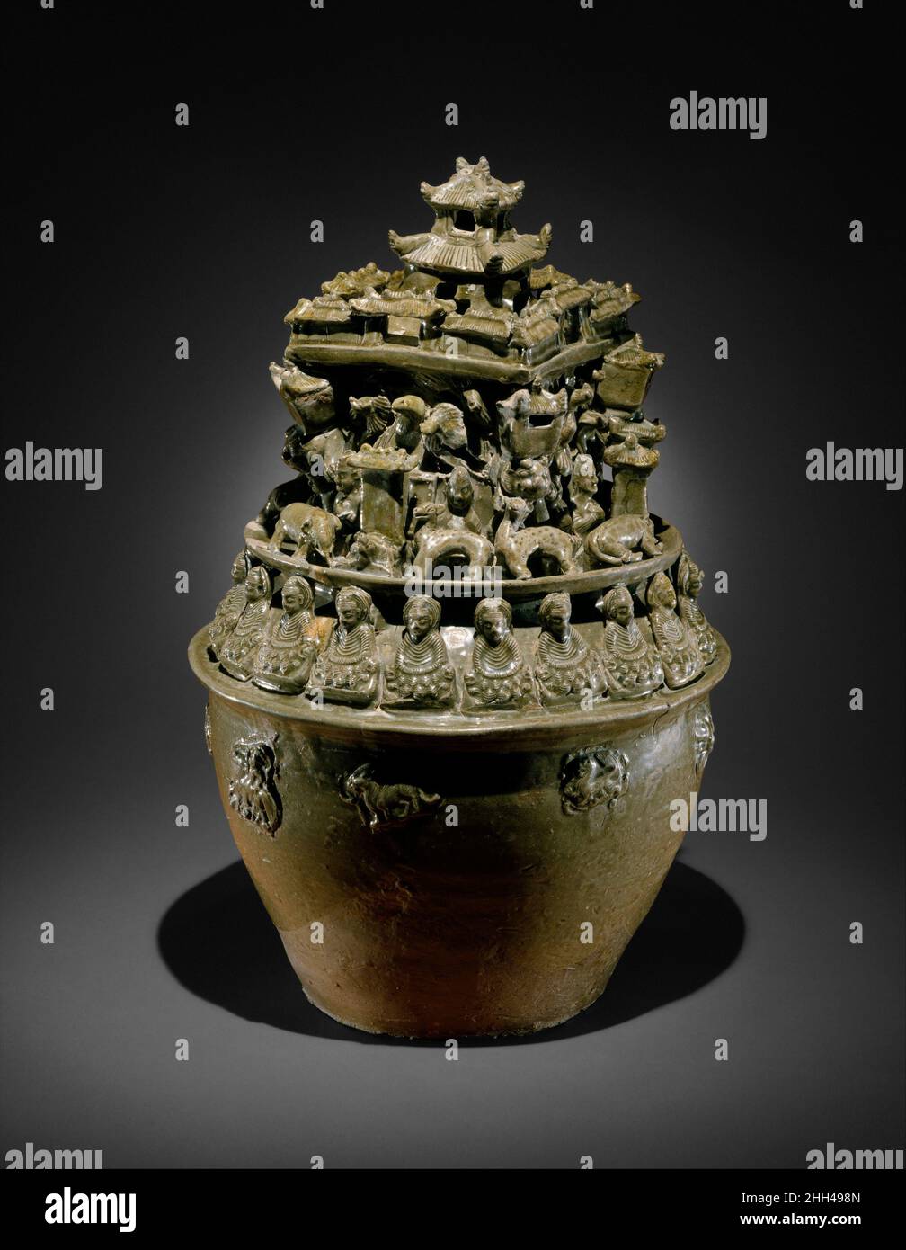 Funerary Urn (Hunping) Chine une théorie moderne sur l'utilisation de cette urne élaborée modélisée est qu'elle peut avoir été destinée à servir de lieu d'habitation éternel pour l'âme du défunt.Il est surmonté d'une structure palatiale céleste tenue en altitude par un troupeau d'oiseaux.Des animaux de compagnie, dont un éléphant et un cerf, entourent le palais.Pour assurer son efficacité, cette vision du paradis par Daoïste est entourée d'une rangée de bouddhas assis dans la méditation sur des thrones de lion avec des pétales de lotus.Ce sont parmi les premières images bouddhistes connues en Chine, et leur présence sur ce navire indique ho Banque D'Images
