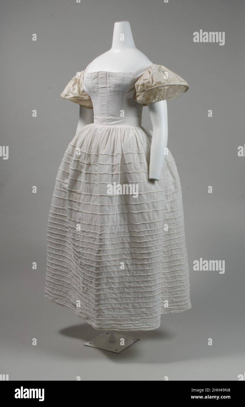 Pjucoat 1830s American les fondations nécessaires pour créer la silhouette 1830s étaient le corset, le pjucoat, et les supports de manches.Ce jupon en coton est câblé et sert au rigidifier dans une forme arrondie qui pousserait les jupes de la robe vers l'extérieur en forme de cloche.Les jupons de cette période étaient également faits de tissu de crin et appelés crinolines (du mot français crin, signifiant crin).Pour créer la taille légèrement relevée, le corset en coton blanc lourd (1987,238) est renforcé avec du cording et du désossage et possède une fente pour un busk au centre à l'avant, ainsi qu'un grand intérieur Banque D'Images