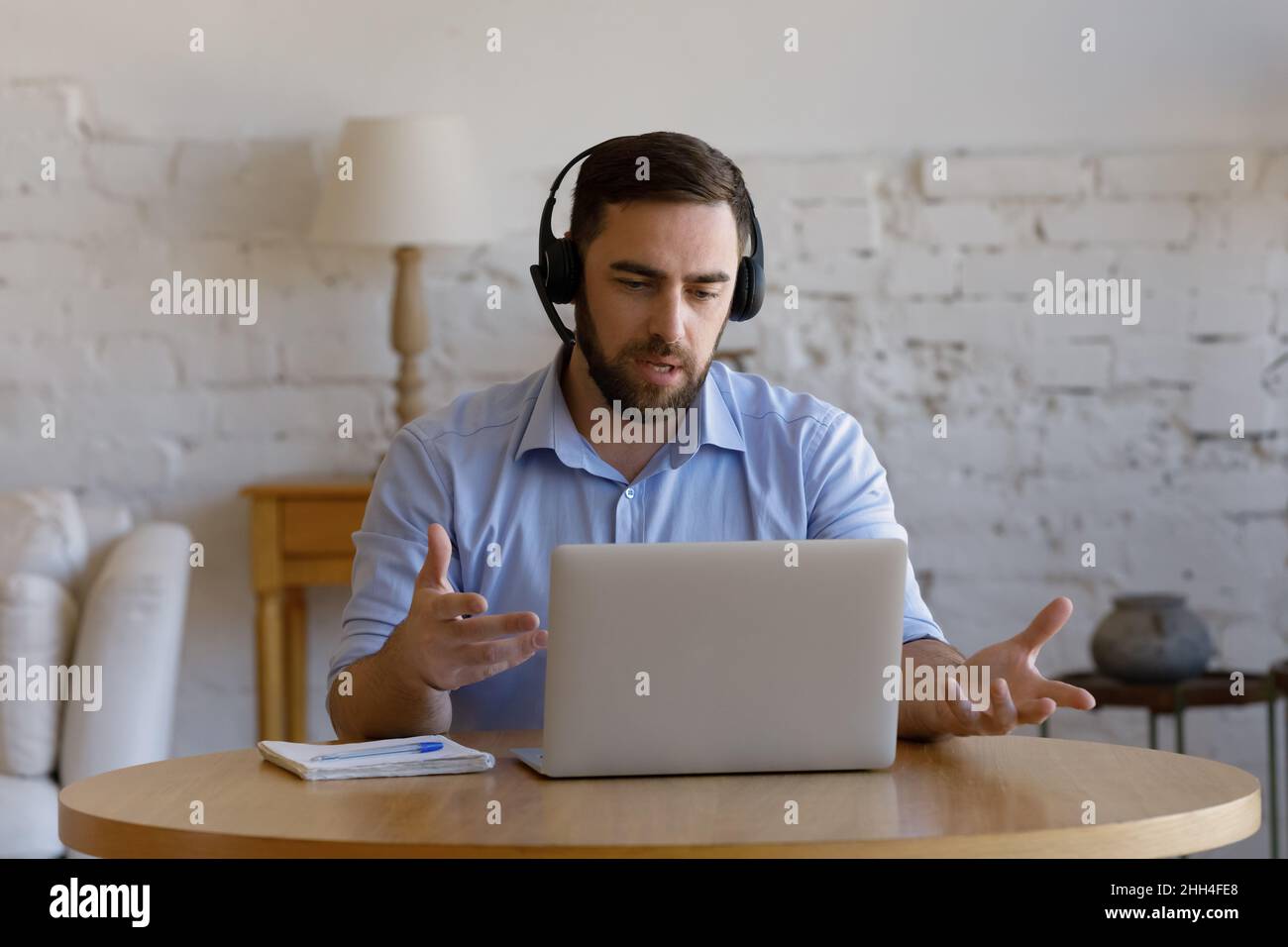 Un homme sérieux enseignant en ligne dans un casque parlant au micro Banque D'Images