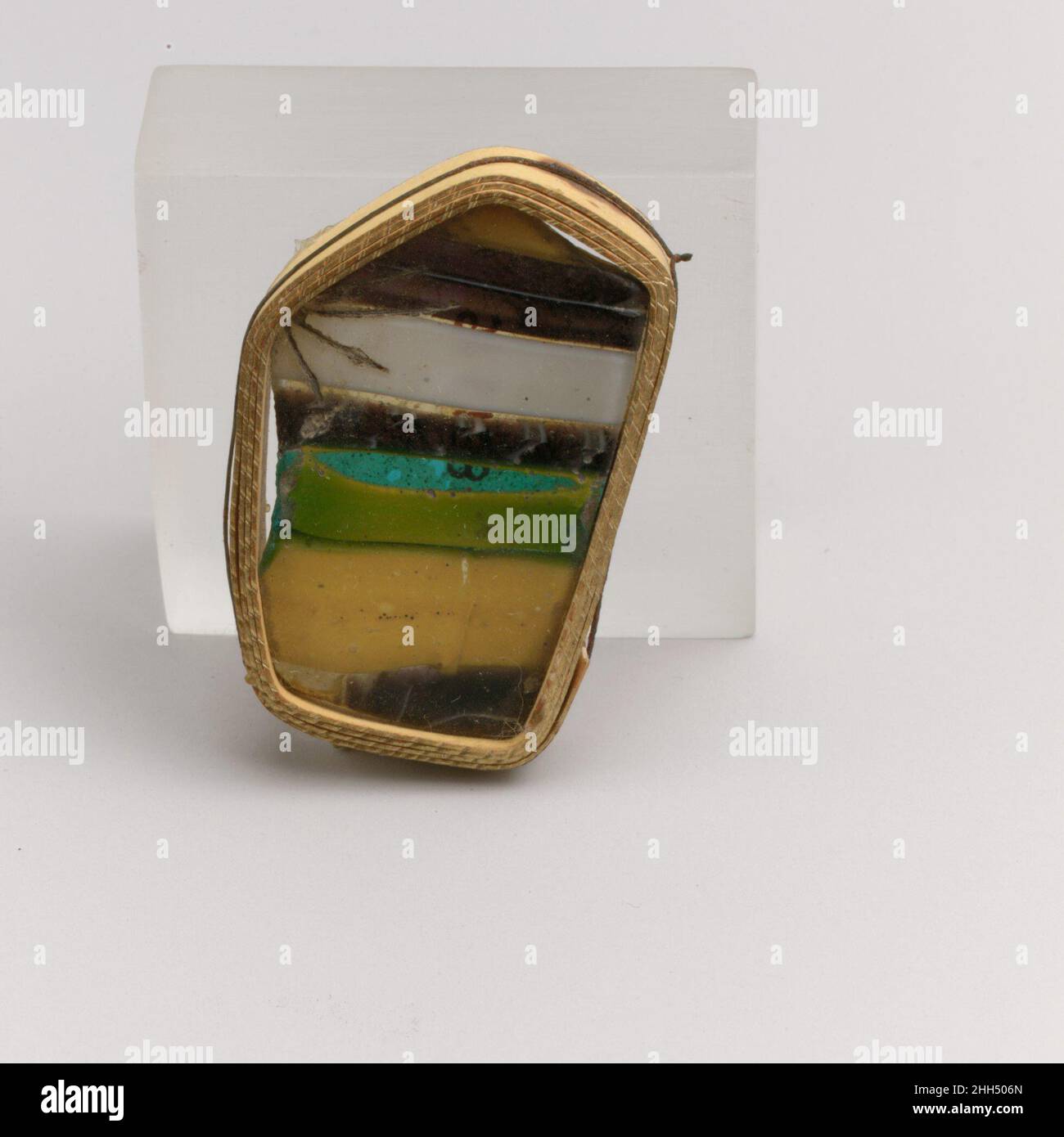 Fragment de mosaïque à rayures de verre fin du 1st siècle C.-B.–début du 1st siècle A.D. fragment de corps romain.violet translucide, bleu turquoise et jaune opaque apparaissant vert, blanc opaque, jaune et incolore.côté incurvé de Convex, partiellement aplati (sur le fond?).orné de bandes parallèles de motif :Jaune, violet avec ligne blanche centrale, blanc, violet avec fil blanc en spirale, turquoise partiellement superposé de jaune, jaune, violet avec ligne blanche, et fines rayures de verre incolore. Piquer et quelques grosses bulles; extérieur poli, avec piqûres de bulles et de fissures de surface; ternir et ir crémeux Banque D'Images