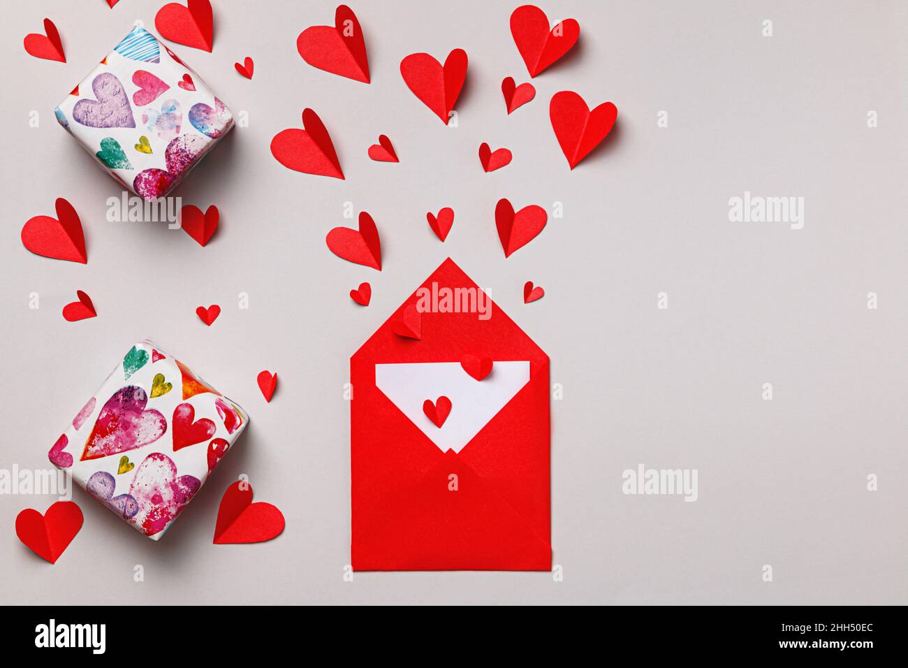 Enveloppe avec lettre d'amour pour la Saint-Valentin.Cadeaux et coeurs en papier sur fond gris. Banque D'Images