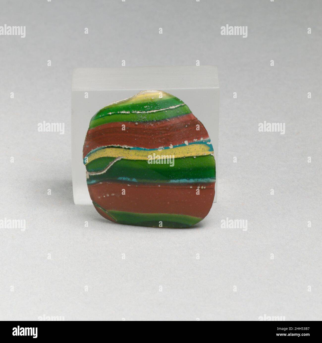 Fragment de bol en mosaïque à rayures de verre fin du 1st siècle C.-B.–début du 1st siècle A.D. fragment de corps romain.bleu turquoise translucide principalement superposé avec jaune apparaissant vert, violet apparaissant opaque brique rouge et jaune opaque.côté à courbure fortement convexe.Décoré de larges bandes formant un motif: Jaune, vert, rouge, bleu turquoise, et vert.extérieur poli,avec piqûres de bulles de surface et altération des fissures de surface ; altération en boeuillage et en irisée crémeuse à l'intérieur et aux bords.Bol en mosaïque à rayures en verre fragment 257249 Banque D'Images