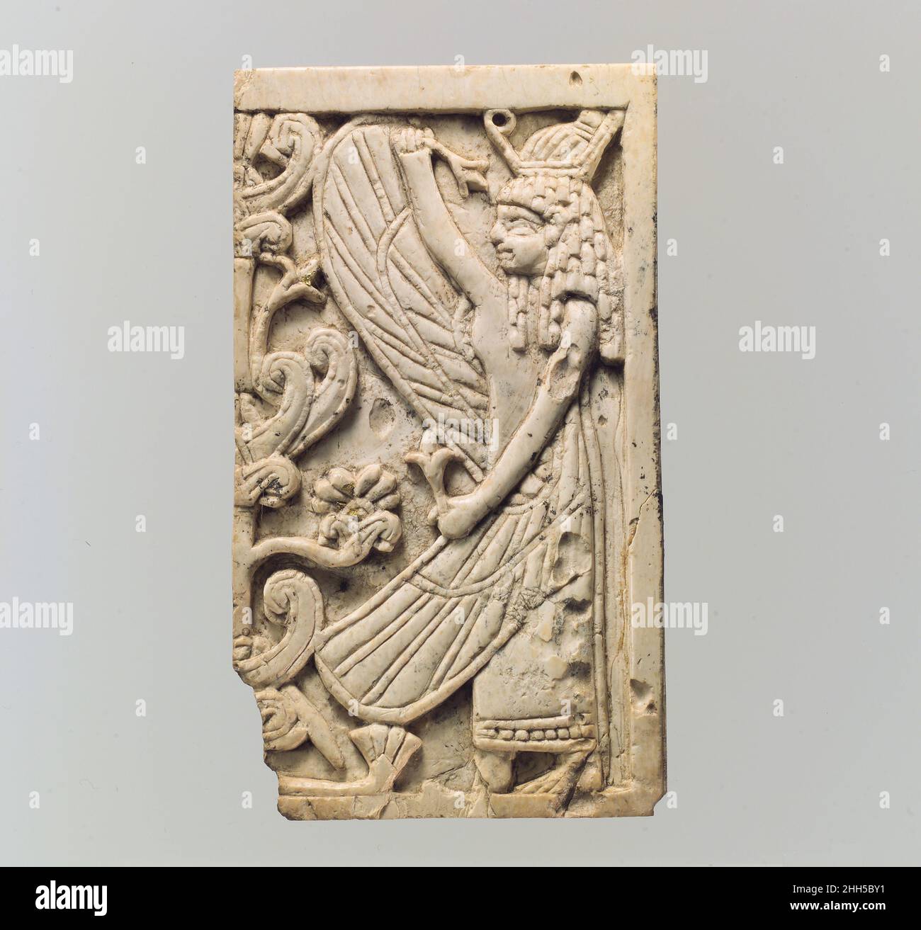 Plaque de mobilier sculptée en relief avec une figure femelle ailé et un “arbre sacré” ca.9th–8th siècle av. J.-C. Assyrien au début du premier millénaire, la sculpture en ivoire était l'un des principaux arts de luxe qui s'épanouissait dans l'ancien proche-Orient.Des défenses d'éléphant ont été sculptées dans de petits objets décoratifs tels que des boîtes cosmétiques et des plaques utilisées pour orner des meubles en bois.Des feuilles d'or, de la peinture et des ornements semi-décoratifs en pierre et en verre animent ces magnifiques œuvres d'art fondées sur certaines caractéristiques stylistiques, formelles et techniques également visibles dans d'autres médias, ont fait des érudits Banque D'Images