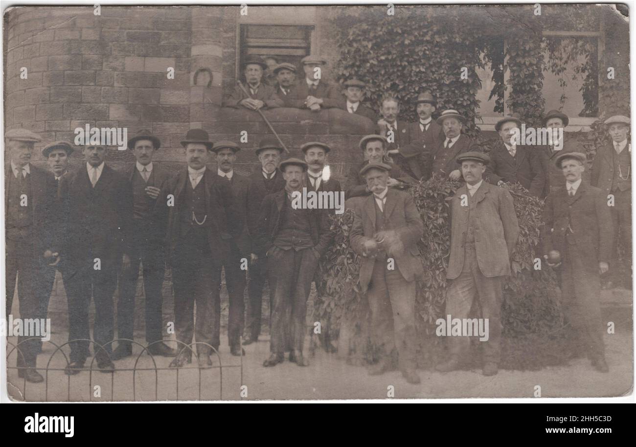 Groupe d'hommes (principalement en casquettes plates) profitant d'un jeu de bols de pelouse, trois hommes tiennent des balles et un (avec des mains floues) se prépare à jeter, début 20th siècle Banque D'Images