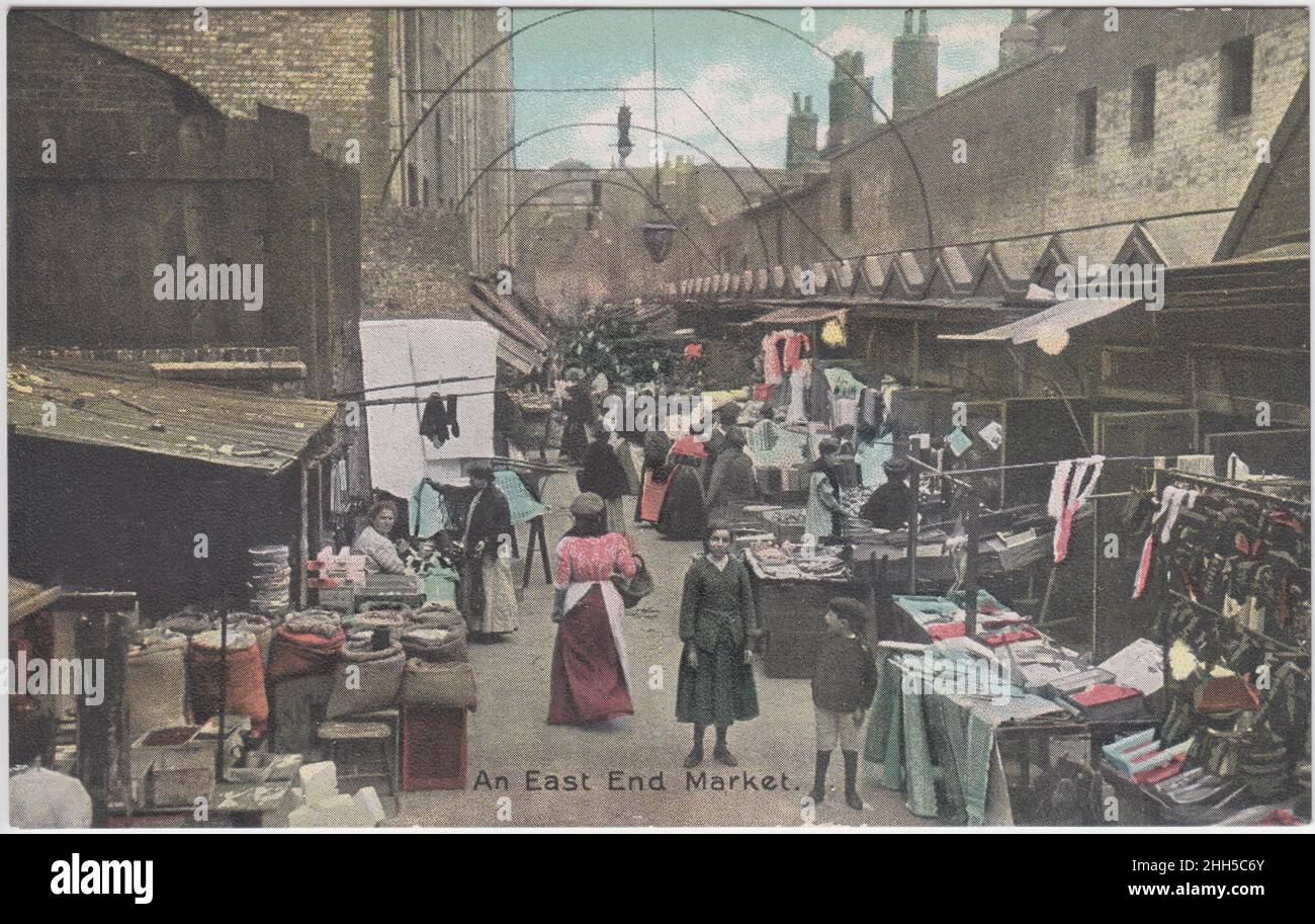 'Un marché East End', début du 20th siècle : étals de marché à l'est de Londres disposés avec des vêtements et d'autres marchandises.Les femmes et les enfants regardent les stands (& vers le photographe) Banque D'Images