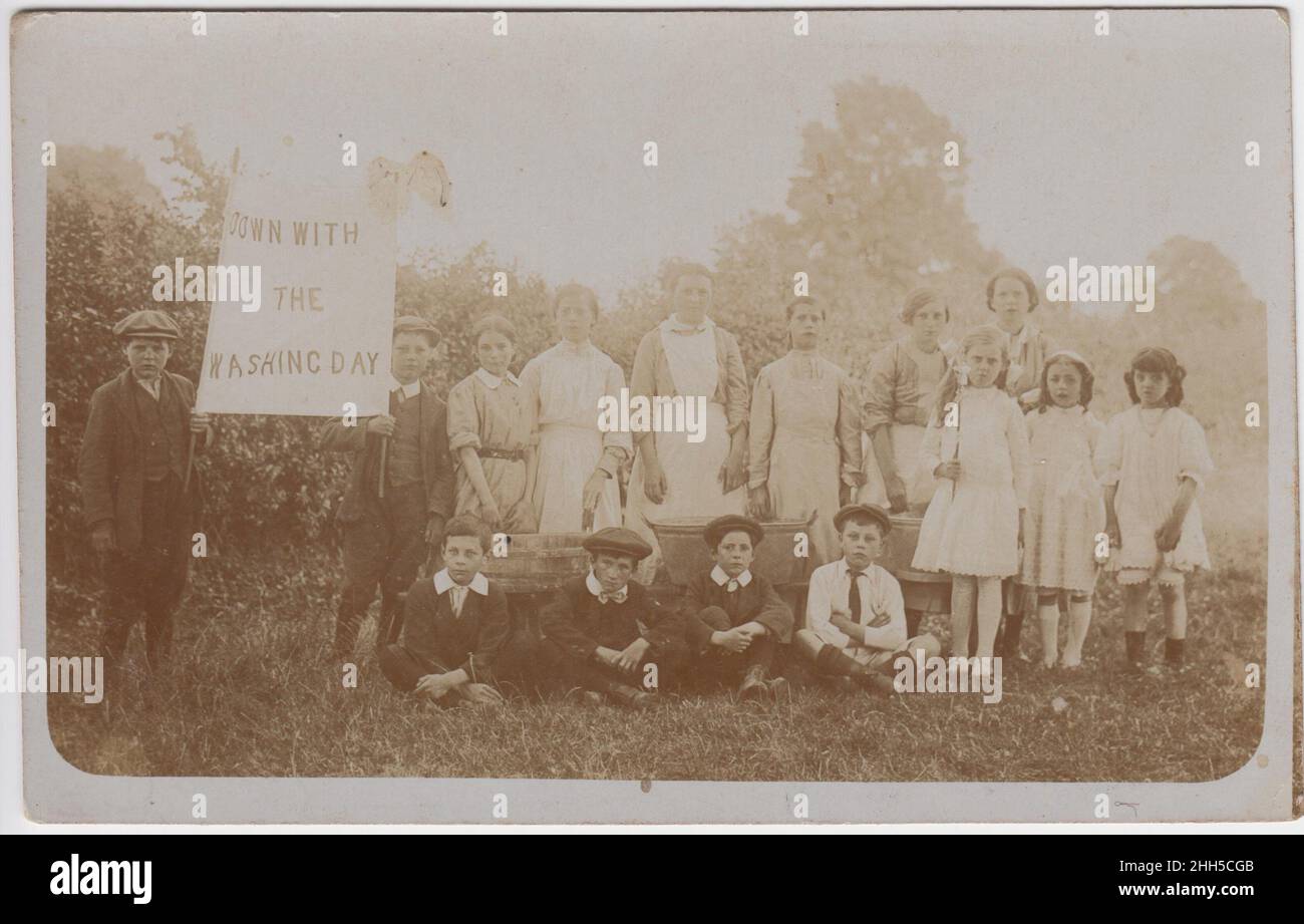 'Débarque avec jour de lavage' : groupe d'enfants dans un champ, rassemblés autour de trois baignoires de lavage.Deux garçons tiennent une bannière qui dit « le jour du lavage », début du 20th siècle Banque D'Images