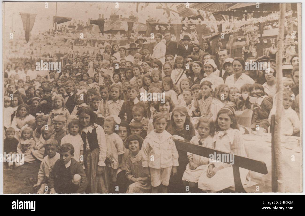 Fête de rue pour le couronnement de George V, 1911: Groupe d'enfants (et quelques adultes) à l'extérieur avec des banderoles suspendues de l'autre côté de la rue. La photo a été prise dans la région de Warwickshire / Oxfordshire, peut-être Stratford sur Avon ou Chipping Norton Banque D'Images