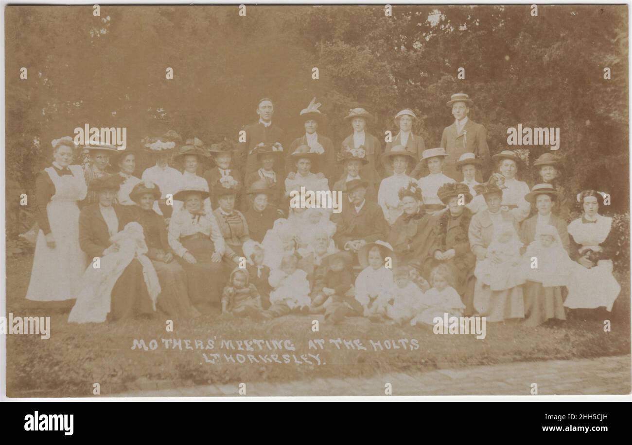 Réunion des mères à The Holts, Little Horkesley, début du 20th siècle.Groupe de femmes portant une gamme de chapeaux, avec des enfants allant des bébés aux tout-petits.Deux hommes sont debout à l'arrière.Plusieurs des femmes semblent être servantes Banque D'Images