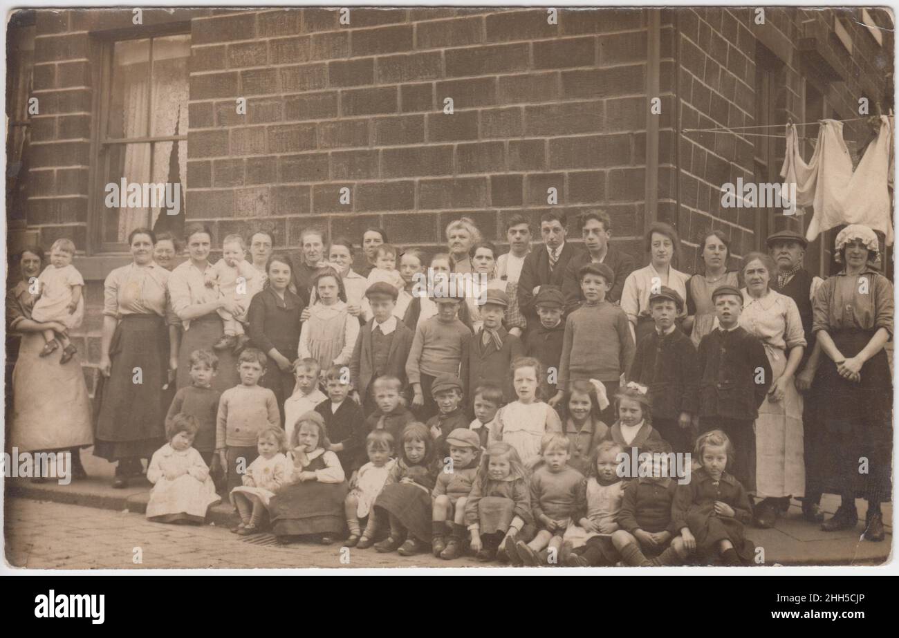Les familles d'une rue de classe ouvrière posant à l'extérieur pour un photographe, début 20th siècle.Les gens à la maison étaient surtout des femmes et des enfants, les vêtements sur une ligne de lavage peuvent être vus en arrière-plan Banque D'Images