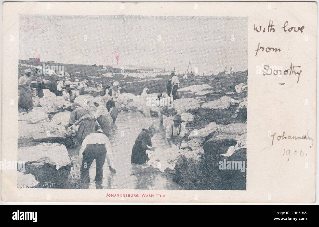 'Bain à laver Johannesburg': Les hommes et les femmes lavant les vêtements / le linge dans un petit étang ou ruisseau.Des lignes de vêtements sont accrochées pour sécher à l'arrière-plan.La carte postale a été envoyée de Johannesburg à Rickmansworth, en Angleterre, en 1903, peu après la fin de la guerre des Boers Banque D'Images