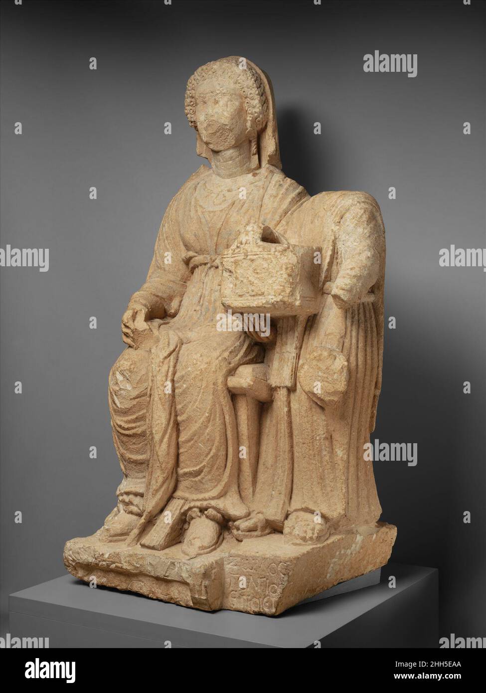 Monument funéraire en calcaire d'une femme 1st siècle A.D. Roman, Cypriote la femme décédée est accompagnée d'une fille servante qui tient une poitrine de bijoux dans sa main droite; un objet rond qui ressemble à un miroir est suspendu de son bras gauche.Les boucles serrées qui encadrent le visage de la femme ont été rendues à la mode dans la cour des empereurs Flavian à Rome vers la fin du premier siècle A.D. le visage de la plinthe sur laquelle se tient le serviteur est inscrit: 'Zoilos de Golgoi fait [il].'.Monument funéraire calcaire d'une femme 242041 Banque D'Images