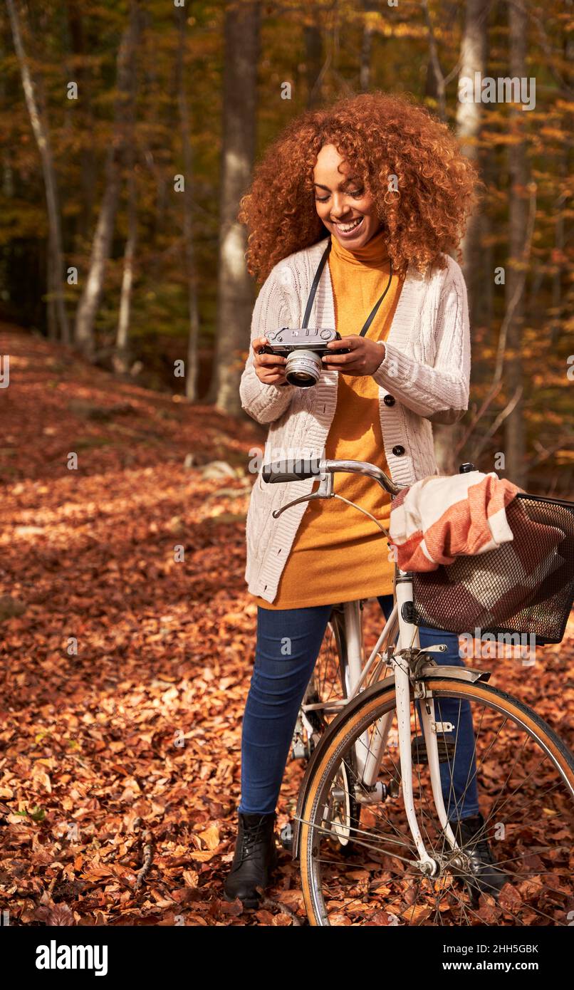 Femme souriante regardant la caméra à vélo dans la forêt d'automne Banque D'Images