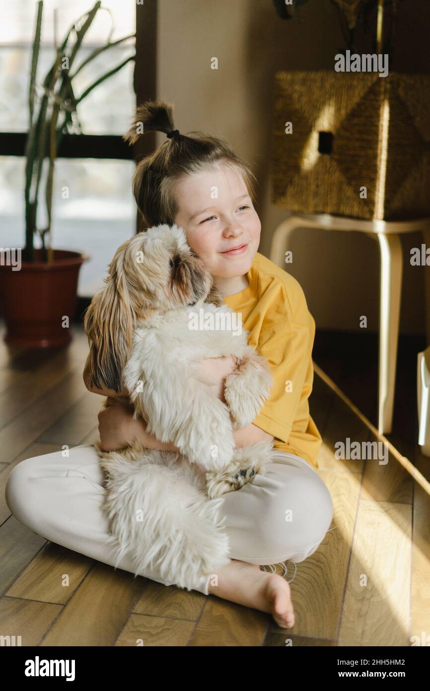 Un garçon souriant embrassant un chien à la maison Banque D'Images