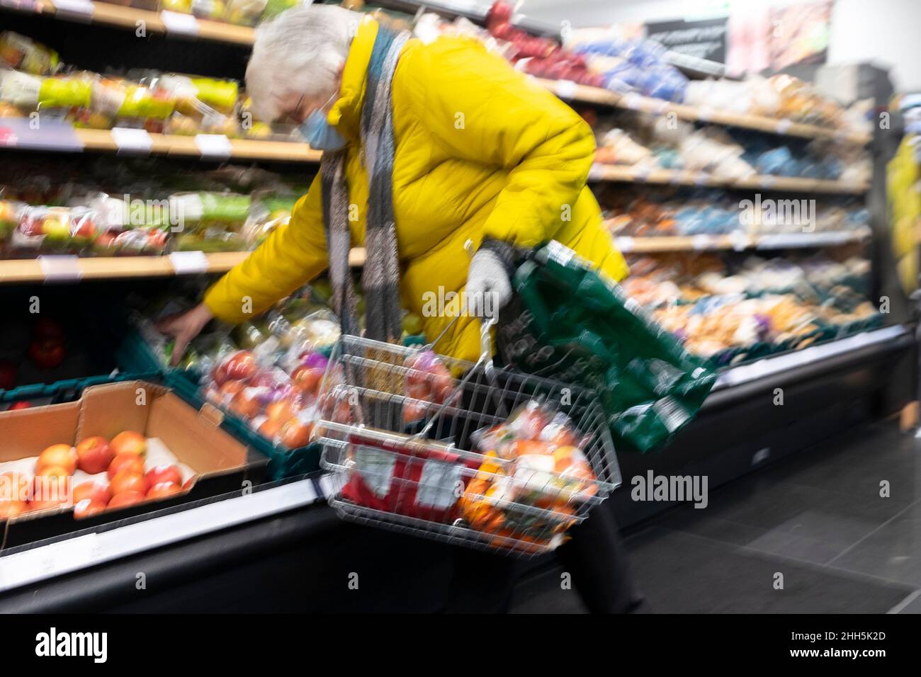 Personne âgée avec panier plié par des étagères pour faire du shopping dans l'allée du supermarché M&S Marks and Spencer janvier 2022 pays de Galles Royaume-Uni KATHY DEWITT Banque D'Images