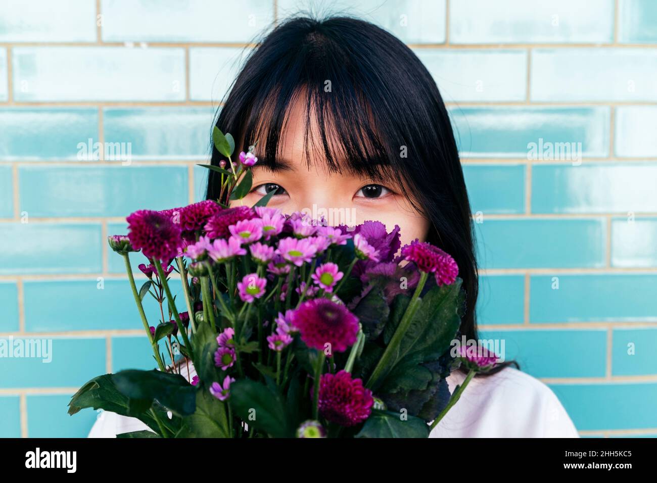Jeune femme tenant un bouquet devant le visage Banque D'Images